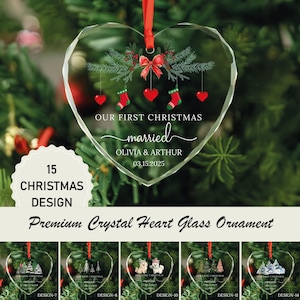May include: A heart-shaped crystal glass ornament with a red ribbon hanger. The design features green pine branches, a red bow, red hearts, and red stockings. Text reads: OUR FIRST CHRISTMAS married OLIVIA & ARTHUR 03.15.2025. The ornament is faceted.