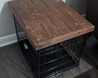 May include: A dark brown wooden top sits atop a black metal dog crate. The crate is on a dark wood floor.