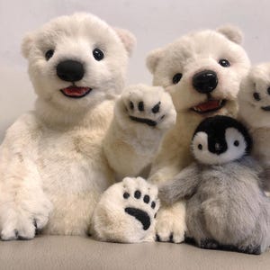 May include: Three plush toys: a white polar bear, a white polar bear cub, and a gray penguin. The polar bears are sitting up and the cub is waving. The penguin is sitting in front of the bears.