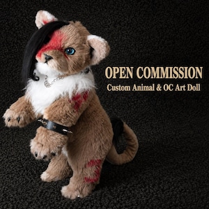 May include: A plush animal art doll with brown fur, white chest fur, and red markings. It features black hair, blue eyes, a silver chain necklace, and a black spiked wristband. The text reads: OPEN COMMISSION Custom Animal & OC Art Doll.