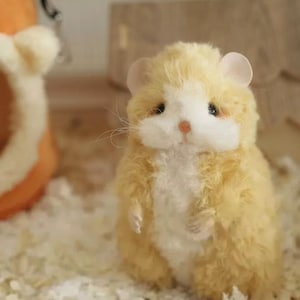 May include: A small, plush hamster toy with a white belly and light brown fur. The toy has a sweet, innocent expression with small, black eyes and a pink nose.