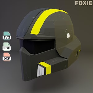 May include: A low-poly style helmet in dark gray with a bright yellow stripe running over the top and a yellow accent near the chin. The helmet features a black visor, a small white skull icon on the side, and the text FOXIE, SVG, PDF, and DXF.