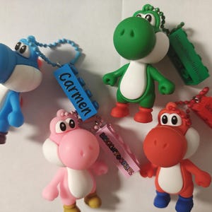 Pode incluir: Quatro chaveiros de personagens Yoshi nas cores azul, rosa, verde e vermelho, cada um com uma barriga branca e preso a um pingente de bloco de montar de plástico. O bloco azul traz o nome Carmen, o rosa diz BRICKUPYOURLIFE e os blocos verde e vermelho contêm texto em alemão.