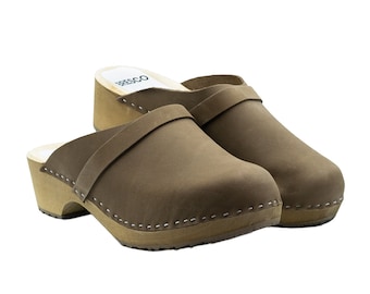 May include: A pair of brown leather clogs with a wooden sole and a strap across the top. The clogs are on a white background.