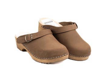 May include: A pair of brown leather clogs with wooden soles. The clogs have a strap with a buckle across the top and the brand name "BRESCO" is visible on the insole. The soles are light brown and the leather is a muted brown color.