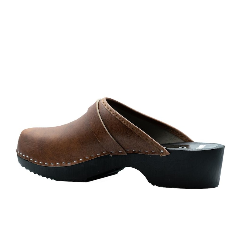 Handmade classic Swedish wooden clogs with a decorative stripe on the upper. Made of natural cowhide in brown leather and black wooden bottom. Available in women and men sizes. Made by BrescoClogs.