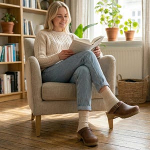 Classic Swedish wooden clogs made of natural cowhide leather in antic brown color and light wooden bottom with orthopedic profile. The upper has a strap with a buckle to adjust the length of the fastening on the heel. Available in women and men size