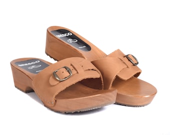 May include: A pair of brown leather heeled sandals with a buckle closure. The sandals are made of wood and have a wooden heel.