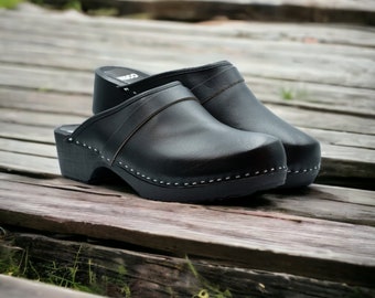 Tamancos suecos clássicos de madeira feitos de couro natural em preto e sola de madeira com faixa decorativa. Feito à mão por Bresco Clogs
