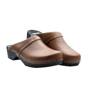 Handmade classic Swedish wooden clogs with a decorative stripe on the upper. Made of natural cowhide in brown leather and black wooden bottom. Available in women and men sizes. Made by BrescoClogs.