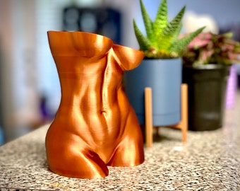 May include: A copper-coloured, 3D printed sculpture of a human torso. The sculpture is smooth and has a metallic sheen.