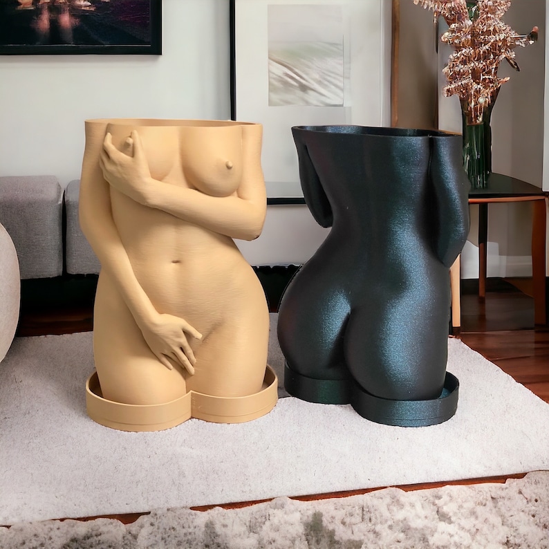 K&ouml;nnte beinhalten: Zwei Pflanzgef&auml;&szlig;e in Form eines menschlichen Torsos. Eines ist in einem Nackt-Beige gehalten, das andere in Dunkelblau.