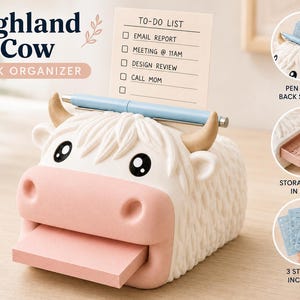 May include: A white and pink Highland cow desk organizer featuring a textured coat, tan horns, and black eyes. The organizer holds a light blue pen across the top and a stack of pink sticky notes in the mouth, with a to-do list card displayed behind.