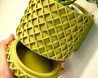 May include: A green, geometric planter with a removable top. The planter is made of a textured material and has a waffle-like pattern.