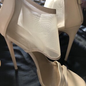 Puede incluir: Un par de sandalias de tac&oacute;n alto beige. Las sandalias presentan un panel de malla en el lateral y un cierre de cremallera en la parte trasera. Los tacones son finos y las correas delgadas. Dise&ntilde;o elegante y con estilo.