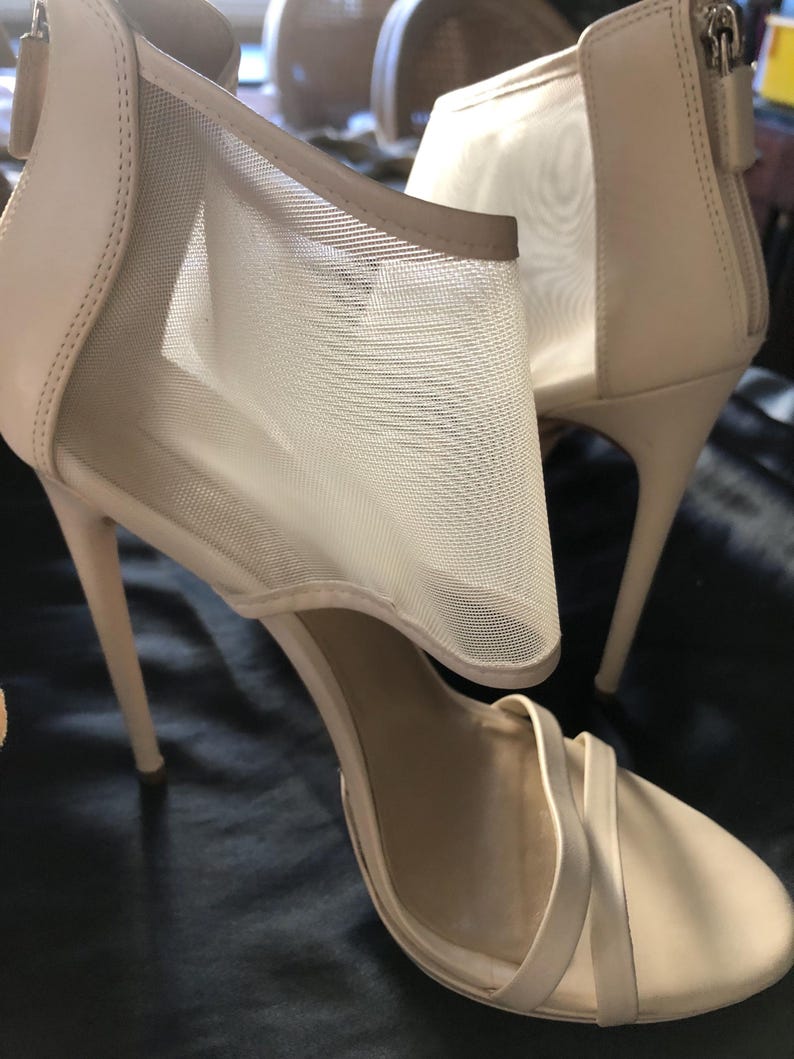 Puede incluir: Un par de sandalias de tac&oacute;n alto beige. Las sandalias presentan un panel de malla en el lateral y un cierre de cremallera en la parte trasera. Los tacones son finos y las correas delgadas. Dise&ntilde;o elegante y con estilo.
