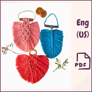 Könnte beinhalten: Drei Makramee-Wandbehänge in Form eines Herzens, eines Blattes und einer Feder. Das Herz ist rot, das Blatt ist rosa und die Feder ist blau. Jeder Behang hat oben eine Holzleiste und unten einen Holzring. Die Behänge werden vor einem weißen Hintergrund gezeigt.