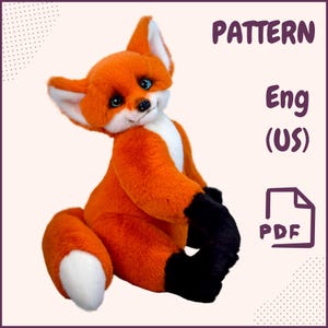 Può includere: Una volpe di peluche con pelliccia arancione brillante, petto bianco e zampe nere. La volpe ha gli occhi blu ed è seduta. L'immagine include il testo "PATTERN Eng (US) PDF".