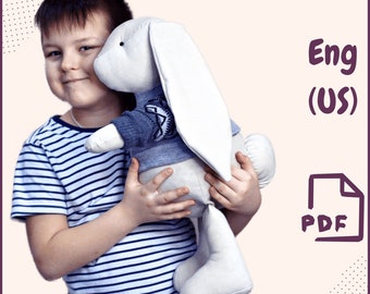 May include: A child is holding a white plush bunny wearing a blue sweater with a white snowflake pattern. The bunny has long, floppy ears. The child is wearing a striped shirt. The text "Eng (US) PDF" is in the top right corner of the image.