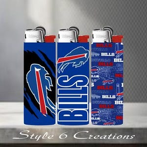 K&ouml;nnte beinhalten: Drei blaue Feuerzeuge mit roten Akzenten, mit Logos und Text des Buffalo Bills Teams. Die Feuerzeuge haben silberne Oberteile und sind mit dem Logo des Teams und dem Wort "BILLS" verziert. Der untere Teil des Bildes tr&auml;gt den Text "Style 6 Creations".