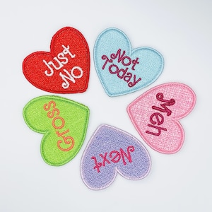 May include: Five heart-shaped patches with embroidered messages. The patches are red, light blue, green, pink, and purple. The messages are "Just No", "Not Today", "Gross", "Meh", and "Next".