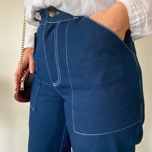 Op de afbeelding: Donkerblauwe spijkerbroek met witte stiksels. De broek heeft een ontspannen pasvorm en heeft een grote zak aan de rechterkant.