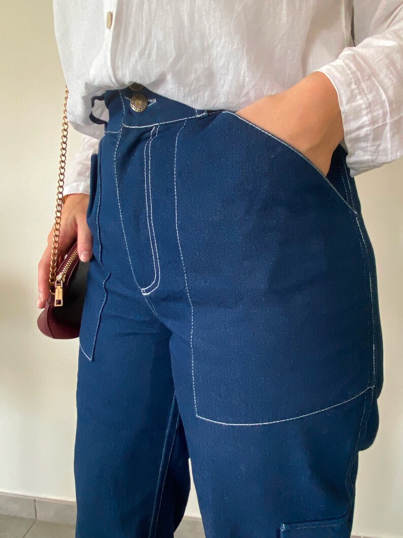 Op de afbeelding: Donkerblauwe spijkerbroek met witte stiksels. De broek heeft een ontspannen pasvorm en heeft een grote zak aan de rechterkant.