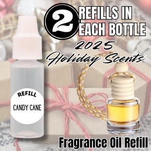 May include: A clear fragrance oil refill bottle with a white cap and a label that reads "Candy Cane." The image also shows a small glass bottle with a wooden top and a gold-colored liquid inside. Text reads "2 Refills in Each Bottle" and "Holiday Scents."