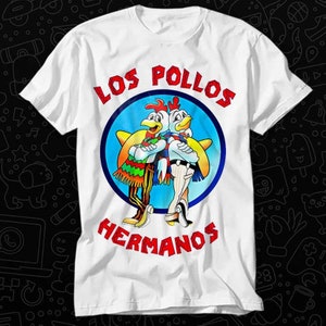 Peut inclure: T-shirt blanc avec un graphique circulaire bleu représentant deux poulets de dessin animé avec le texte "Los Pollos Hermanos" en rouge.