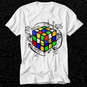 May include: White t-shirt with a colorful Rubik's Cube graphic and mathematical equations. The cube is surrounded by arrows and lines, creating a geometric design.