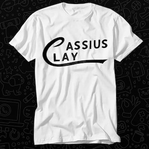 May include: White t-shirt with a black graphic that says "Cassius Clay" in a curved font.