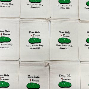 Puede incluir: Bolsas con cord&oacute;n de color crema con un dise&ntilde;o tem&aacute;tico de golf. Cada bolsa presenta una ilustraci&oacute;n de un campo de golf verde con una bandera roja y el texto "Same Hole Forever". Debajo del gr&aacute;fico est&aacute; el texto "Steve's Bachelor Party October 2025."