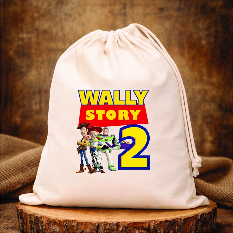 Puede incluir: Una bolsa blanca con cord&oacute;n, con el texto "WALLY STORY 2" en amarillo y rojo, con los personajes de dibujos animados Woody, Jessie y Buzz Lightyear. La bolsa est&aacute; sobre una superficie de madera.