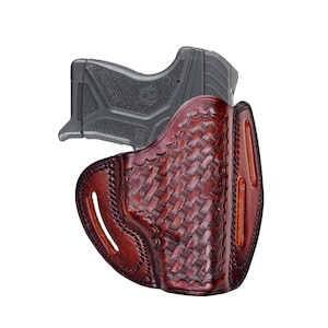 Op de afbeelding: Een bruine leren holster met een geweven patroon, ontworpen om een ​​zwart pistool te houden. De holster heeft een riemlus en een trekkerbescherming.