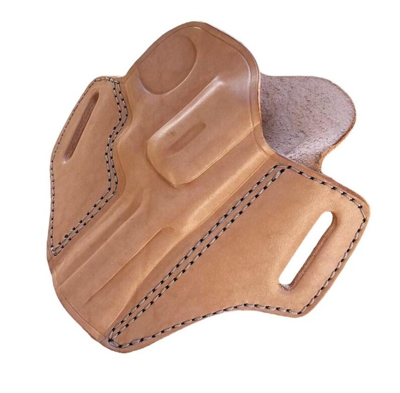 May include: A light brown leather holster with black stitching. The holster has a molded shape with a curved design and several openings. The edges are reinforced with stitching.