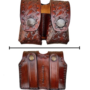 May include: A brown leather double magazine pouch with a basket weave pattern and silver snap closures. The pouch is designed to hold two magazines and is made of durable, high-quality leather. The bottom of the pouch has a decorative stitched design.