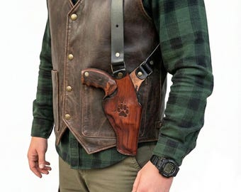 Peut inclure: Un holster d'épaule en cuir marron avec une arme à feu en cuir marron assortie. Le holster est porté sur un gilet en cuir marron et une chemise à carreaux verte. Le holster a un motif de patte.