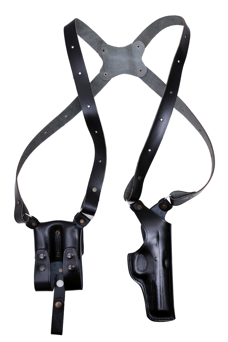 May include: Black leather shoulder holster with two holsters for carrying handguns. The holster has adjustable straps and is designed for concealed carry.