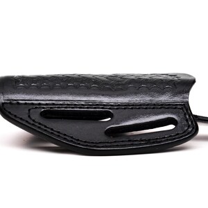 Op de afbeelding: Een zwart leren holster met een gestructureerd ontwerp en uitsparingen voor een pistool.