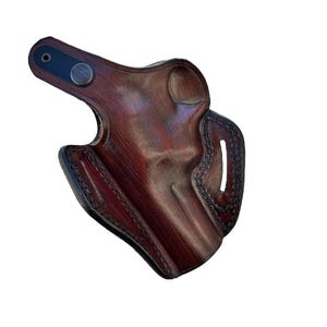 Peut inclure: Un &eacute;tui en cuir marron avec un motif cousu et un bouton en m&eacute;tal. L'&eacute;tui est con&ccedil;u pour contenir une arme &agrave; feu.