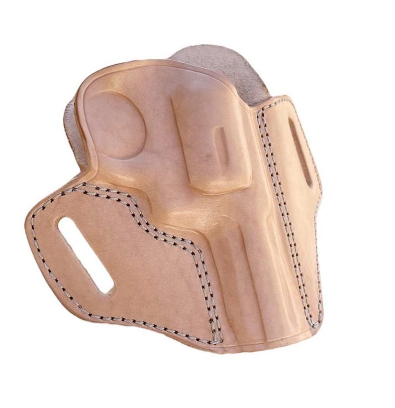 May include: A light tan leather holster with a molded design. The holster features a stitched border with black thread and a cutout for a belt clip. The leather has a natural, unpainted finish.