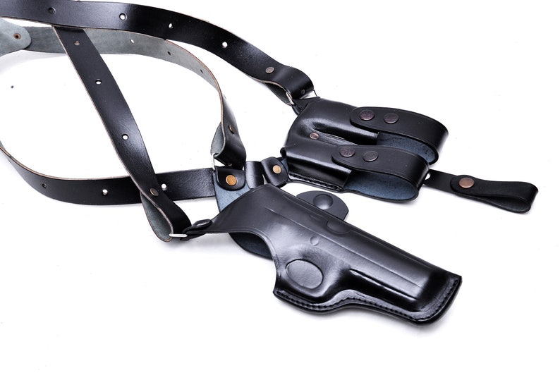 May include: A black leather shoulder holster for a handgun. The holster has adjustable straps and a magazine pouch.