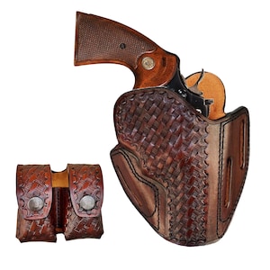 May include: A brown leather holster with a woven design, holding a revolver with a wooden grip. A matching double magazine pouch is to the left. The leather has a rich, textured appearance.