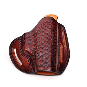 Op de afbeelding: Een bruine leren holster met een geweven patroon. De holster heeft een riemlus en een trekkerbescherming.