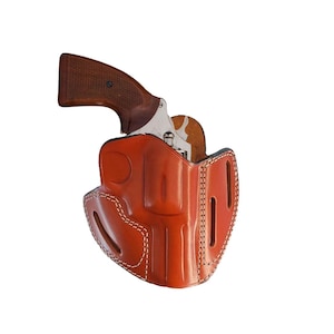 Può includere: Un fodero in pelle marrone con cuciture bianche per un piccolo revolver.