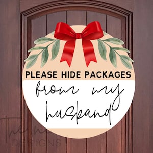 May include: A round, peach-colored sign with a red bow and green leaves. The sign says "PLEASE HIDE PACKAGES from my husband".