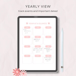 Op de afbeelding: Een digitale tablet met een jaaroverzicht en twaalf roze maandvakken. Het scherm toont handgeschreven tekst voor evenementen zoals Etsy Restock, Mayfair en Christmas Bazaar. Een witte stylus ligt naast de tablet op het oppervlak.