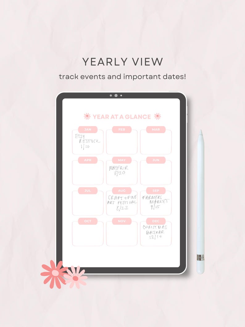 Op de afbeelding: Een digitale tablet met een jaaroverzicht en twaalf roze maandvakken. Het scherm toont handgeschreven tekst voor evenementen zoals Etsy Restock, Mayfair en Christmas Bazaar. Een witte stylus ligt naast de tablet op het oppervlak.