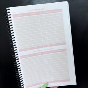 May include: A spiral bound notebook with a pink and white gridded page. The page is labeled "Inventory Goal" and "Inventory Completed". The notebook is used for tracking inventory.