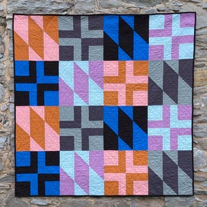 Può includere: Una trapunta quadrata caratterizzata da un motivo a griglia geometrica composto da sedici blocchi. Il design incorpora una vivace tavolozza di colori rosa, arancione, nero, blu, azzurro, viola e grigio scuro, rifinita con un bordo nero.